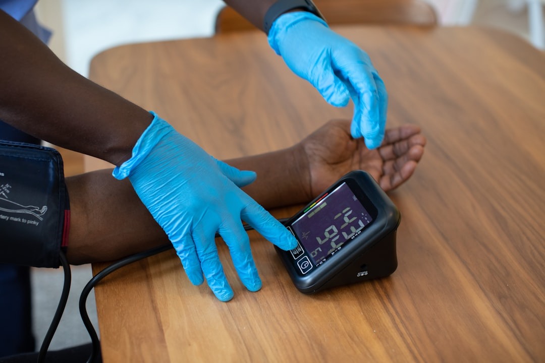 Healthcare professional checks patient's blood pressure with digital monitor.